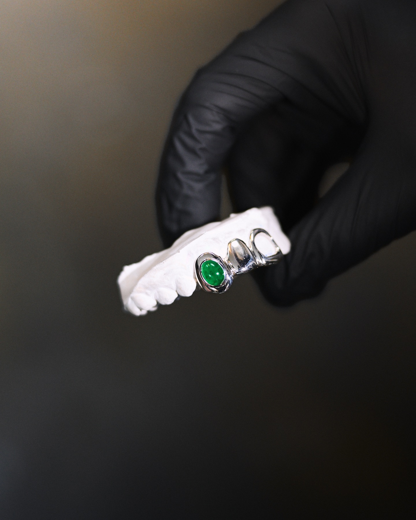 Grillz en or blanc serti d'une pierre verte sur moulage dentaire