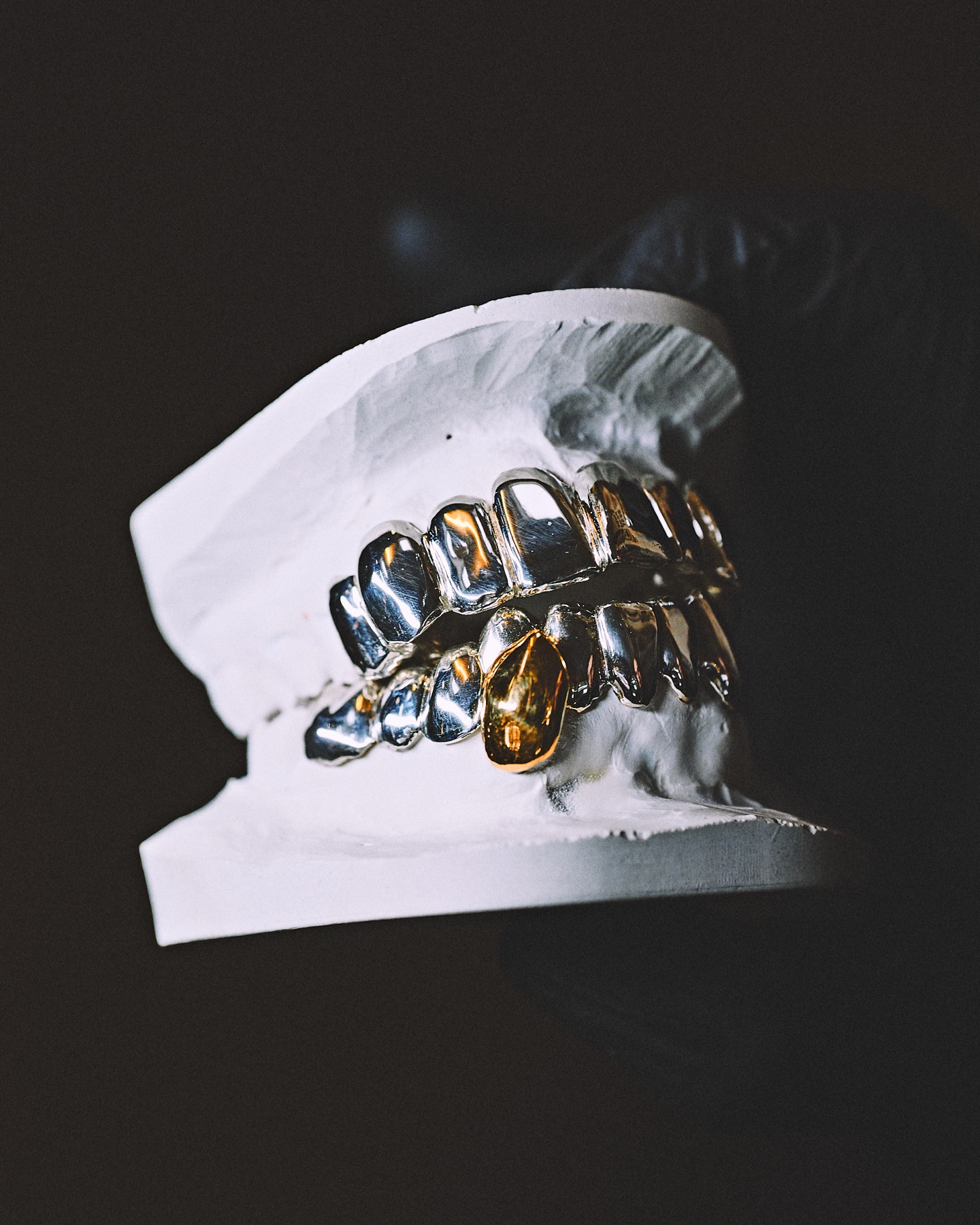 Grillz argent et or posé sur son modèle en plâtre, à l'atelier